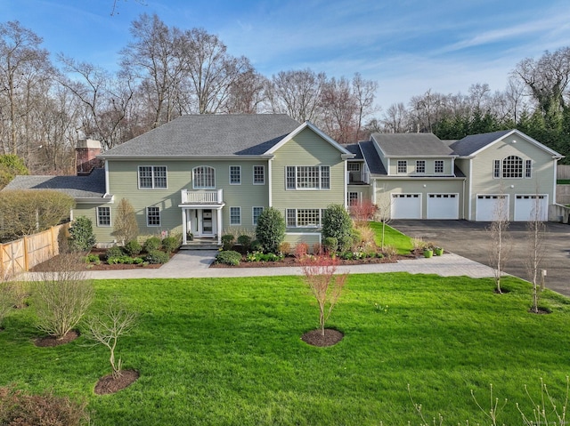 view of front of property featuring a chimney, aphalt driveway, an attached garage, roof with shingles, and a front yard