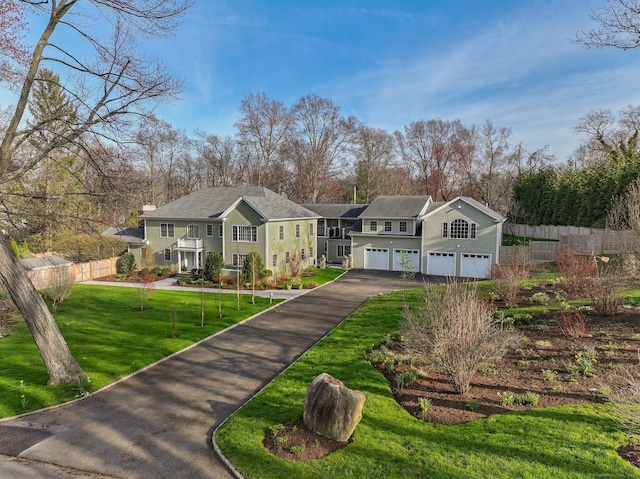 view of front of property featuring an attached garage, a front lawn, driveway, and fence