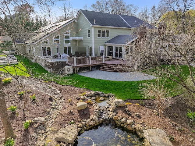 rear view of property with a yard, roof with shingles, and a deck
