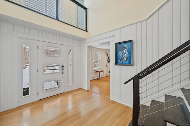 entrance foyer with a baseboard radiator, wood finished floors, and a high ceiling