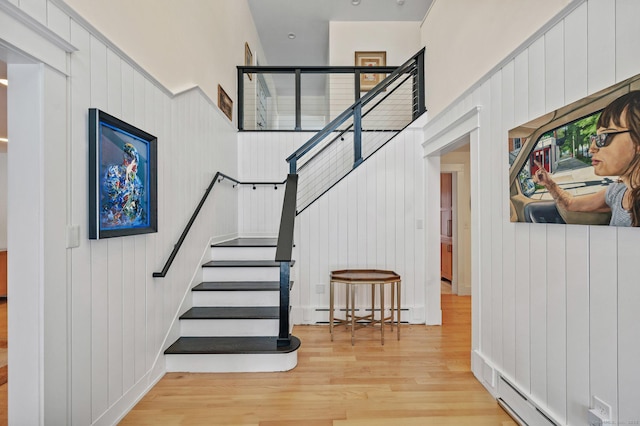 stairway featuring baseboard heating and wood finished floors