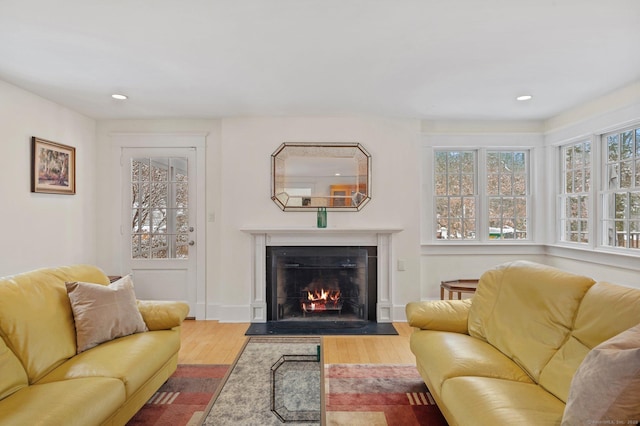 living room with a fireplace with flush hearth, wood finished floors, recessed lighting, and a healthy amount of sunlight