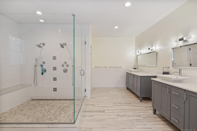 full bath featuring recessed lighting, two vanities, a stall shower, and a sink