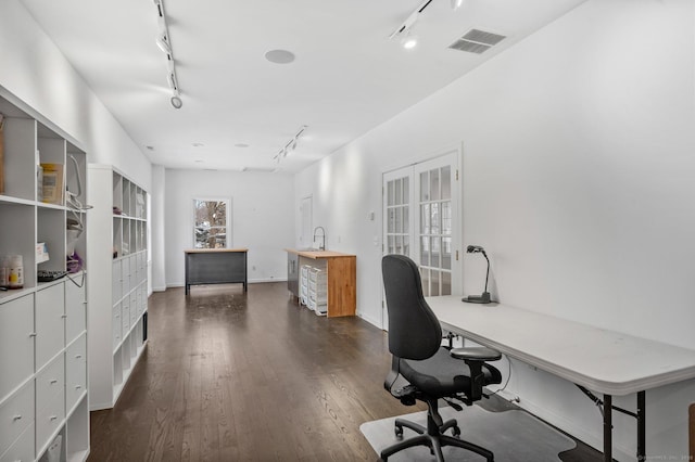 office space featuring dark wood finished floors, track lighting, visible vents, and baseboards