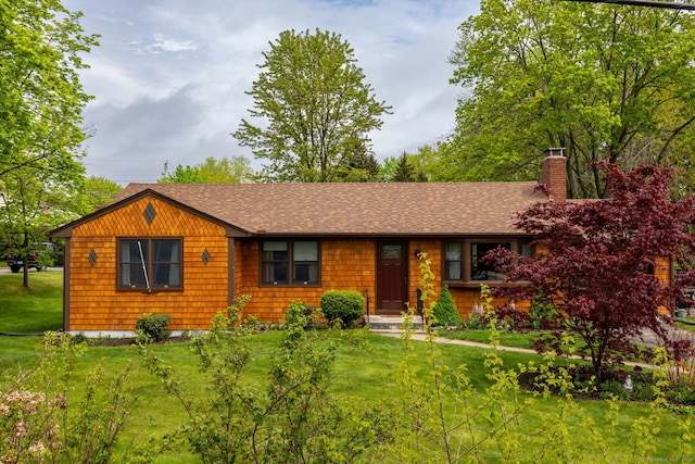 view of front of home featuring roof with shingles, a chimney, and a front yard