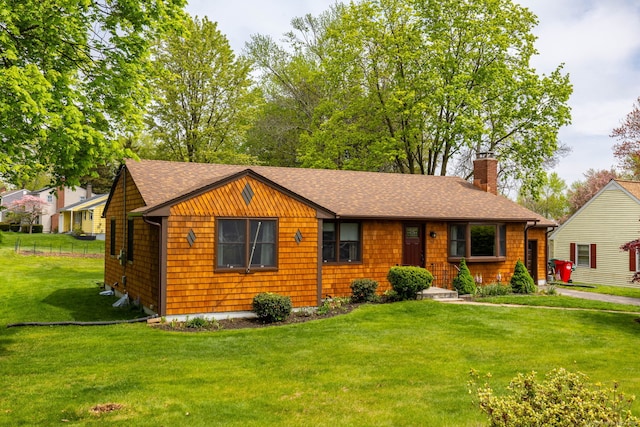 view of front facade with roof with shingles, a front lawn, and a chimney
