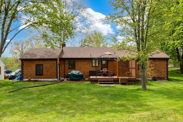 rear view of house featuring a gazebo, a wooden deck, a chimney, a lawn, and a shingled roof