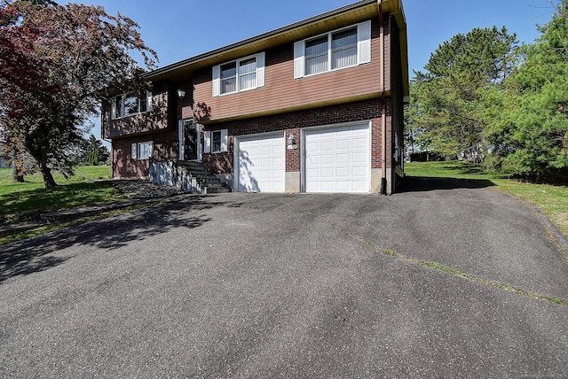 split foyer home with brick siding, a garage, and driveway
