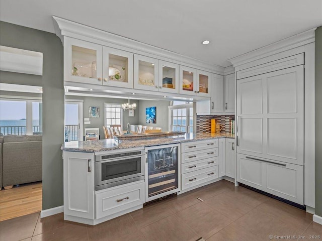 50 Grove Way, Clinton, CT 06413 - interior space featuring a peninsula, white cabinetry, glass insert cabinets, light stone countertops, and beverage cooler
