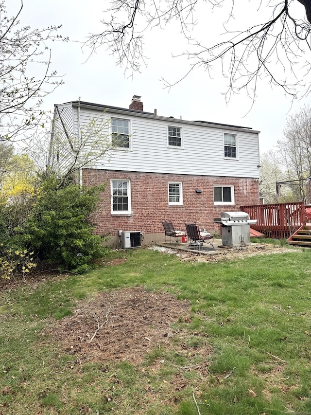 136 Oberlin Rd, Hamden, CT 06514 - back of property featuring a chimney, a wooden deck, brick siding, a yard, and a patio