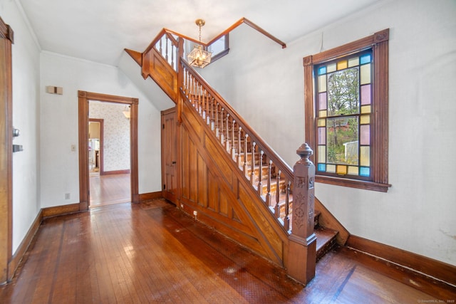 staircase featuring a chandelier, hardwood / wood-style floors, crown molding, and baseboards