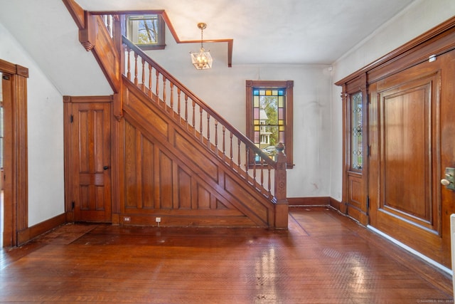foyer featuring dark wood-style flooring, baseboards, a notable chandelier, and stairs