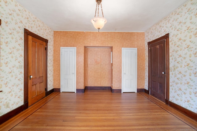 empty room featuring light wood-style flooring and wallpapered walls