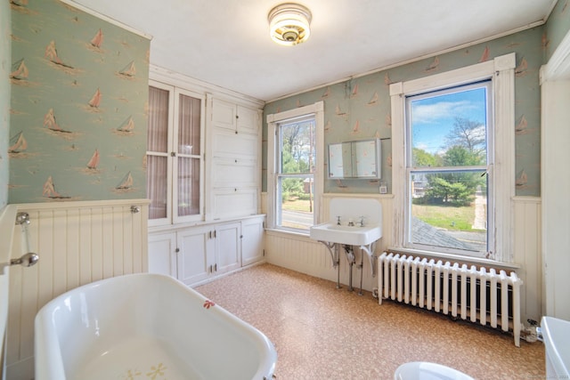bathroom featuring radiator, a wainscoted wall, a freestanding bath, and radiator heating unit