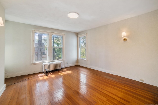 spare room featuring baseboards, wood-type flooring, and radiator