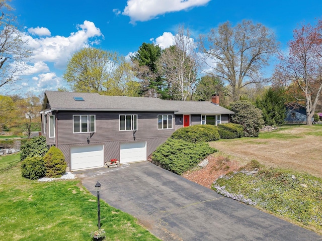 view of front of house featuring a chimney, a front lawn, driveway, and an attached garage