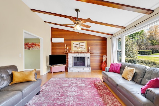living room featuring lofted ceiling with beams, a stone fireplace, light wood-type flooring, a ceiling fan, and wooden walls