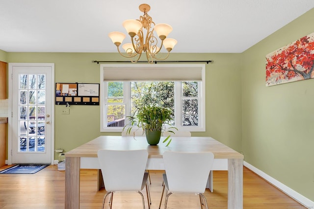 dining space featuring a chandelier, baseboards, and light wood-style floors