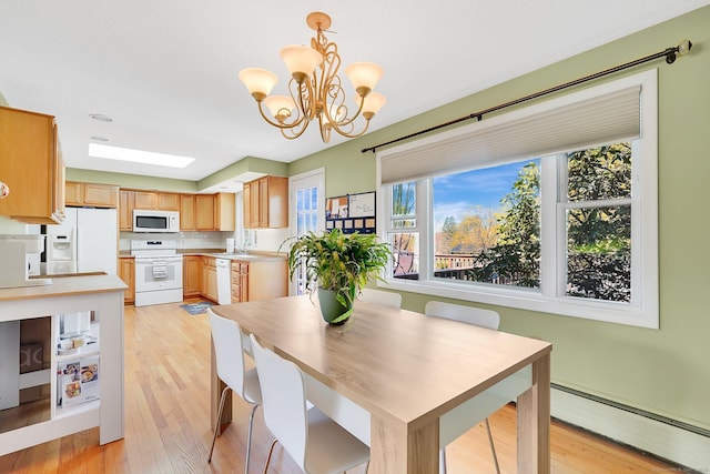 dining area with a notable chandelier, a baseboard heating unit, and light wood finished floors