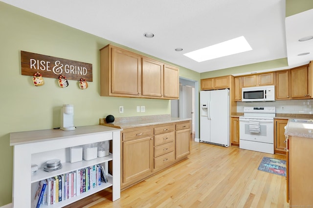 kitchen with tasteful backsplash, a skylight, white appliances, light wood-style floors, and light countertops