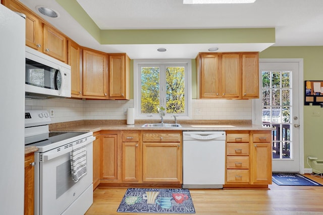kitchen featuring white appliances, plenty of natural light, light countertops, and a sink