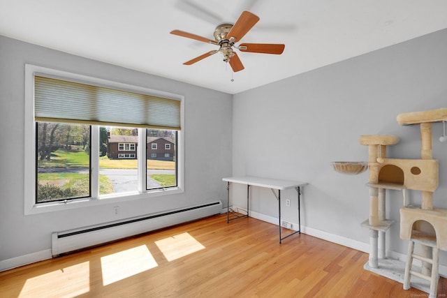 unfurnished room with baseboard heating, baseboards, wood finished floors, and a ceiling fan