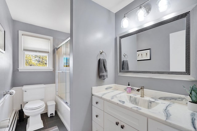 bathroom with tile patterned flooring, a baseboard heating unit, toilet, vanity, and bath / shower combo with glass door