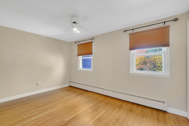 empty room with light wood-style flooring, baseboard heating, a wealth of natural light, and baseboards
