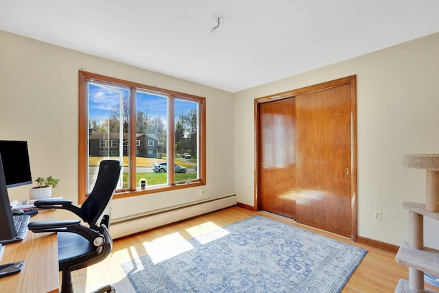 office space featuring a baseboard radiator, light wood-style floors, and baseboards