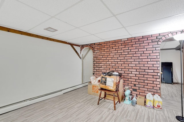 interior space with brick wall, a paneled ceiling, baseboard heating, and arched walkways