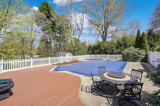 view of swimming pool featuring a deck, a fenced backyard, a fenced in pool, and a patio area