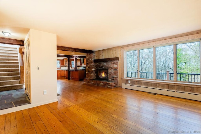 15 Fox Den Rd, Danbury, CT 06811 - unfurnished living room featuring a baseboard heating unit, hardwood / wood-style flooring, a fireplace, and stairway