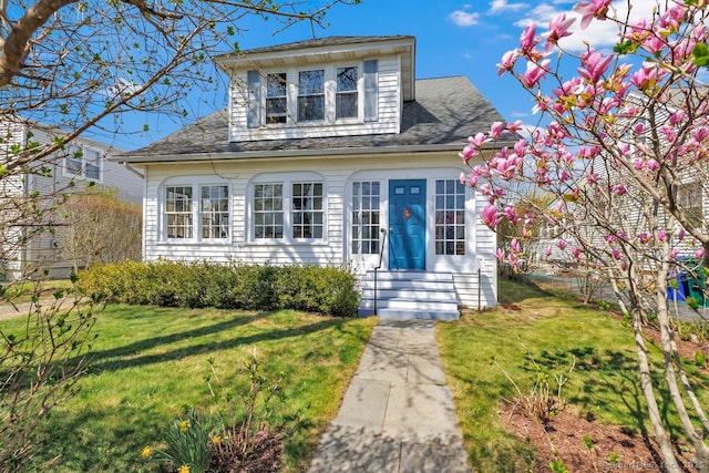 view of front of home featuring entry steps, a shingled roof, and a front yard