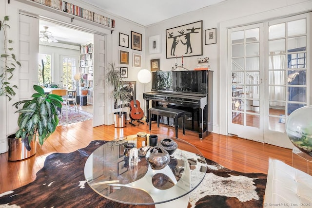 living area with a ceiling fan, crown molding, and wood-type flooring
