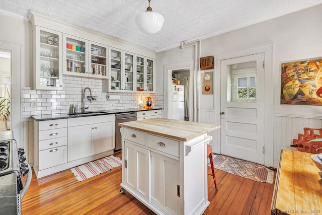 kitchen with decorative backsplash, wood counters, stainless steel appliances, light wood-style floors, and a sink