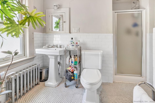 bathroom with radiator, tile walls, toilet, and a shower stall