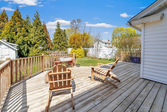 wooden deck with an outdoor structure, a storage unit, and a fenced backyard