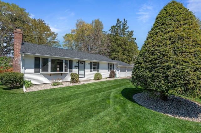 view of front of house featuring a chimney, a shingled roof, a front yard, and a garage