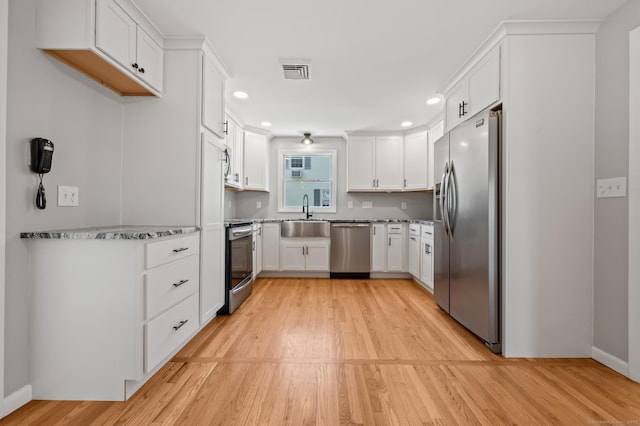 kitchen featuring visible vents, light wood-type flooring, white cabinetry, a sink, and appliances with stainless steel finishes