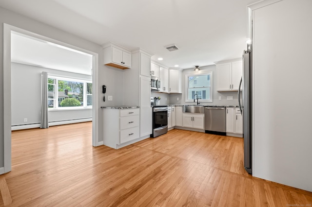 kitchen featuring stainless steel appliances, plenty of natural light, a sink, and light wood-style floors
