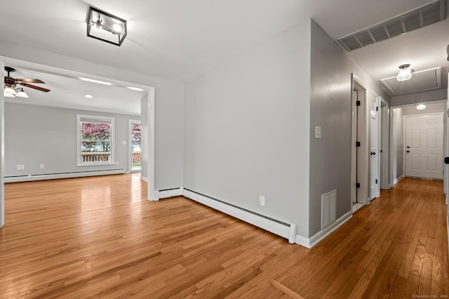 corridor with a baseboard radiator, visible vents, attic access, light wood-type flooring, and a baseboard heating unit