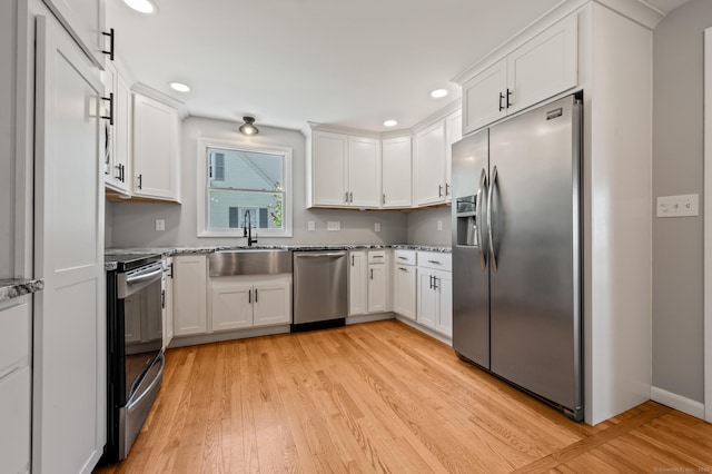 kitchen with recessed lighting, a sink, appliances with stainless steel finishes, and light wood-type flooring