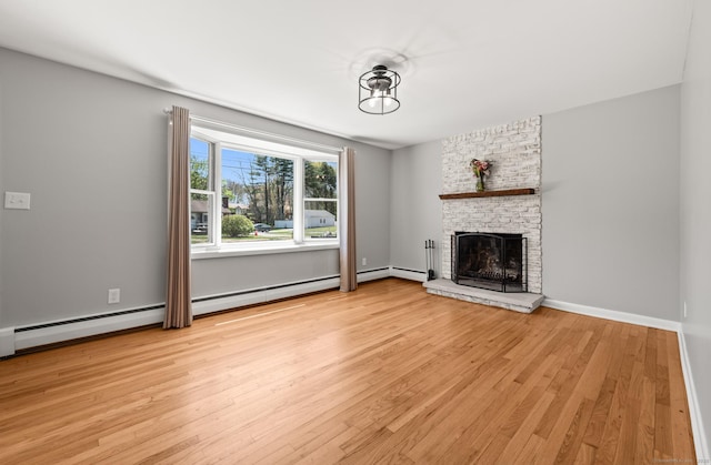 unfurnished living room featuring baseboards, light wood-style flooring, and a brick fireplace
