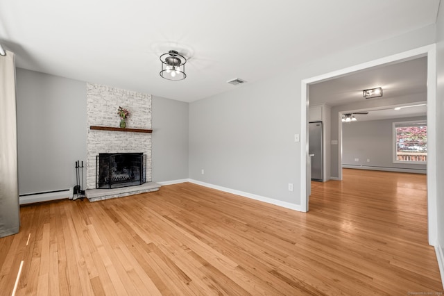 unfurnished living room with visible vents, a baseboard radiator, a fireplace, and light wood-type flooring