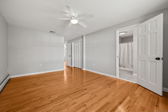 unfurnished bedroom featuring visible vents, ensuite bathroom, baseboards, a baseboard radiator, and light wood finished floors