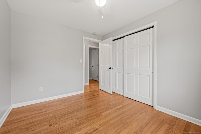 unfurnished bedroom with baseboards, light wood-style flooring, and a closet