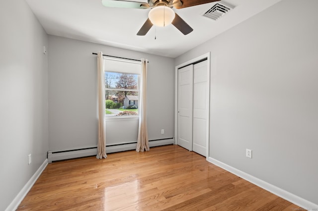 unfurnished bedroom featuring visible vents, a ceiling fan, baseboards, light wood-type flooring, and a baseboard heating unit