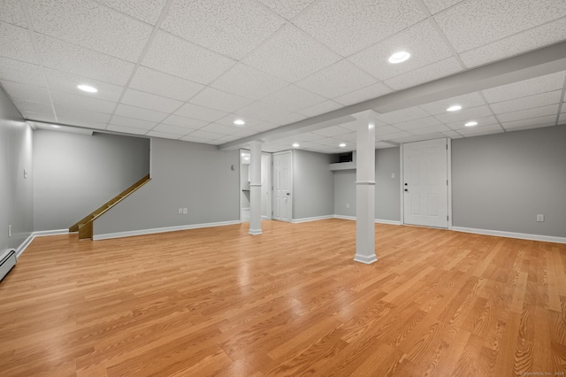 finished basement with recessed lighting, light wood-style flooring, baseboards, and a paneled ceiling