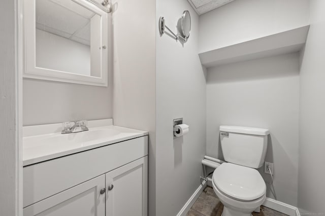 bathroom with baseboards, toilet, and vanity