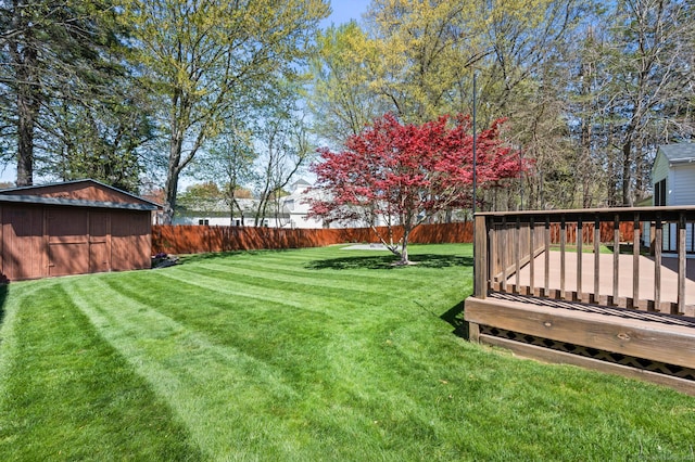 view of yard featuring a deck, an outbuilding, a shed, and a fenced backyard